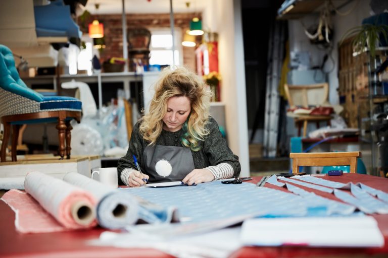 A woman preparing, measuring and cutting upholstery fabric on a workbench