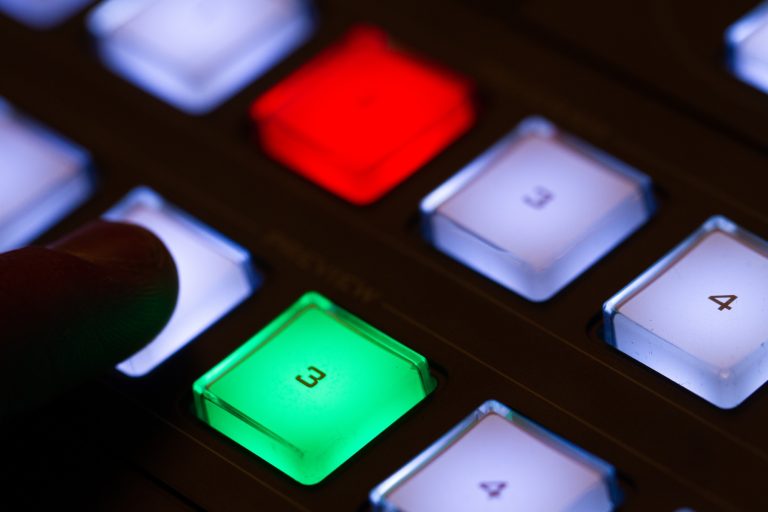 Hand operating video production switcher, television, audio visual buttons,user using media switcher