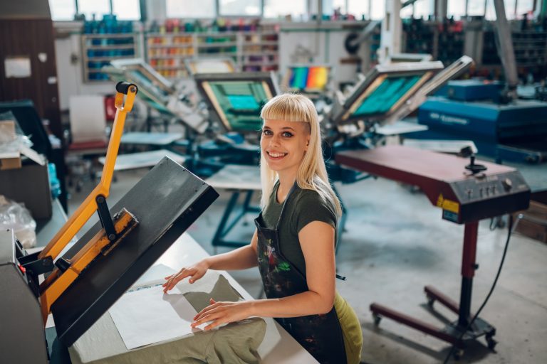 Portrait of print shop worker using heating press on textile product