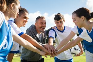 Team of young football players stacking hands before match